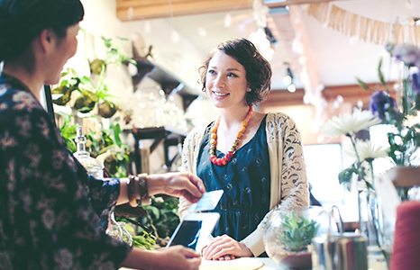 A merchant running a card through a tablet payment square