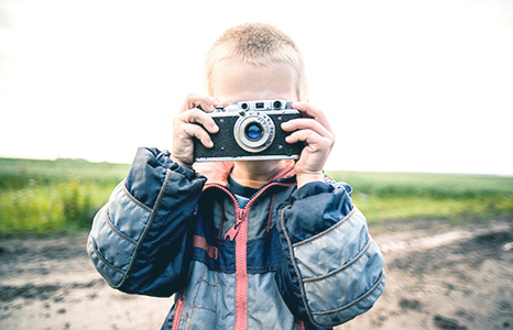 A small child looking through the lens of a camera