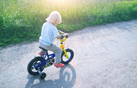 A small child riding a bike with training wheels
