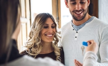 A smiling couple being handed their house keys