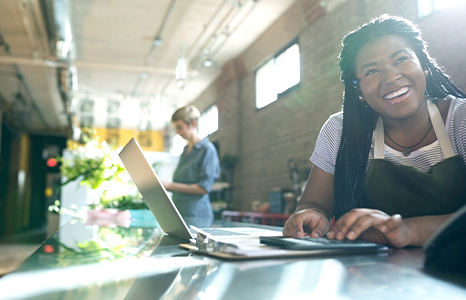 A woman smiling while using her laptop in a cafe