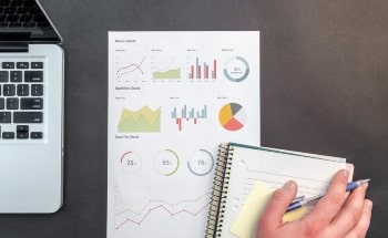 Analysis charts and graphs on a piece of paper next to a laptop