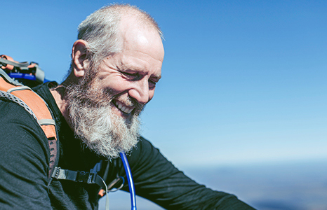 Older active man with water pack smiling and looking down